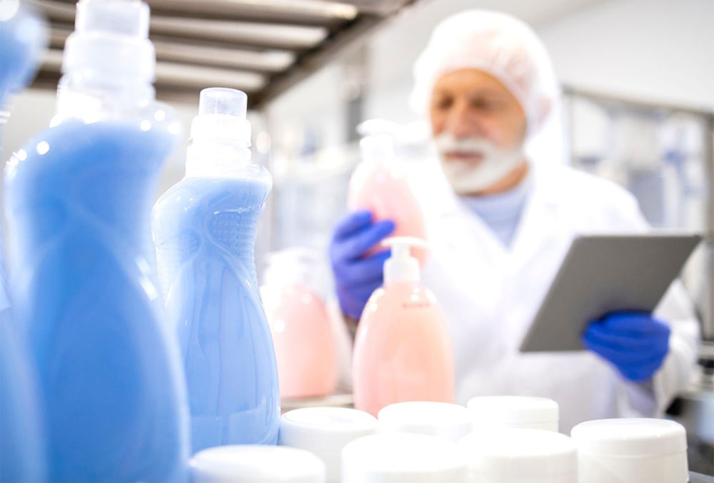 Packaging machinery for cleaning and detergent products — stainless-steel filler, conveyor and nozzles.